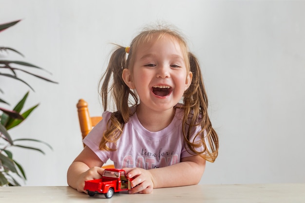 Little girl playing with a small red toy car