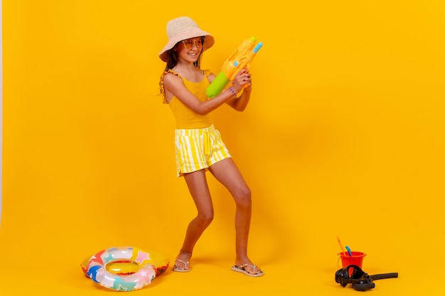 Little girl playing with summer toys on a yellow background