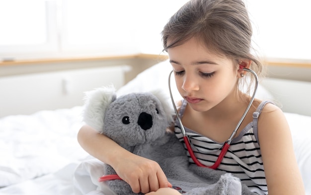 A little girl plays doctor with her favorite soft toy