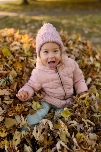 A little girl plays in a pile of autumn foliage