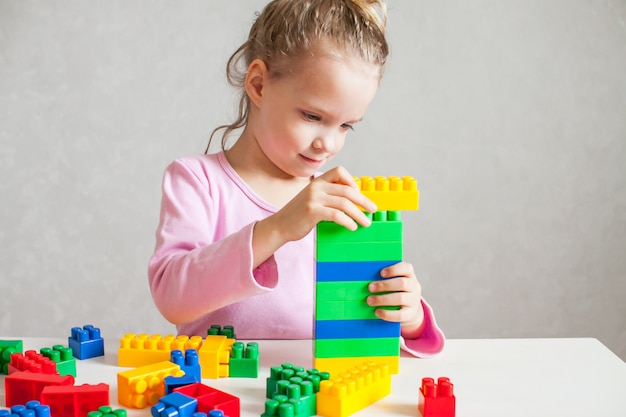 Little girl plays with multi-colored plastic constructor