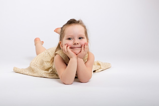 Little girl poses in beautiful dress on grey background