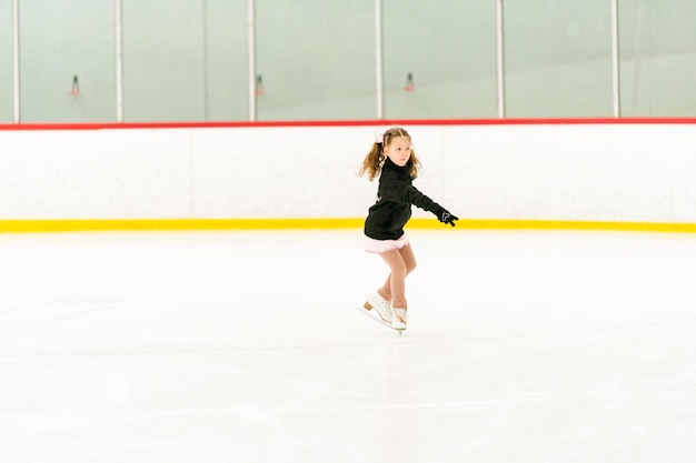 Little girl practicing figure skating on an indoor ice skating rink