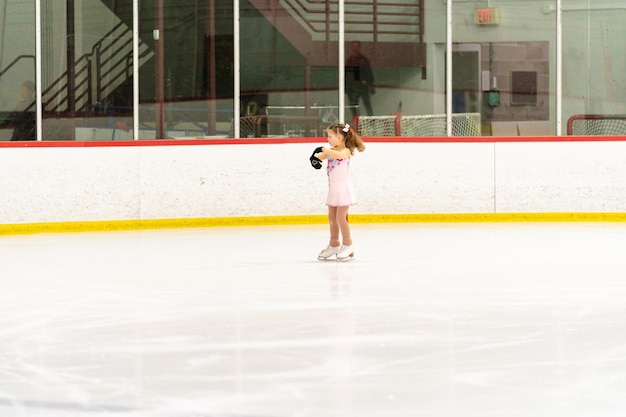 Little girl practicing figure skating on an indoor ice skating rink