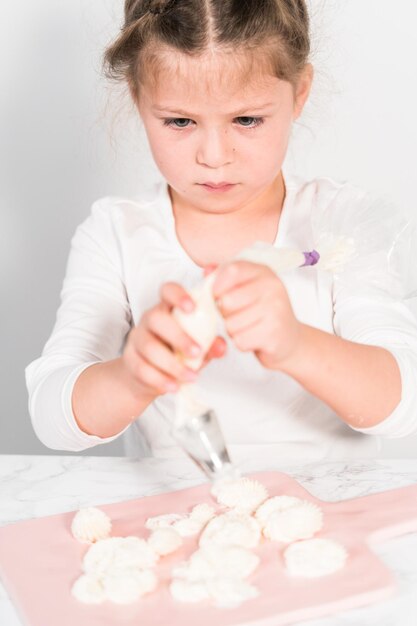 Little girl practicing piping Italian buttercream frosting.