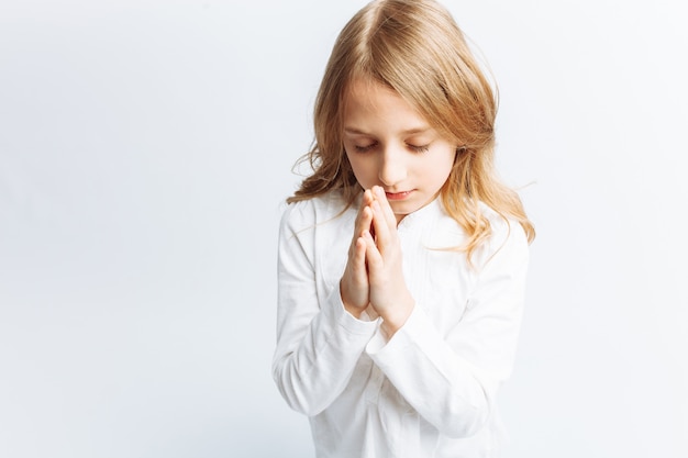 Little girl praying on her knees to God, communion with God, sweet and beautiful