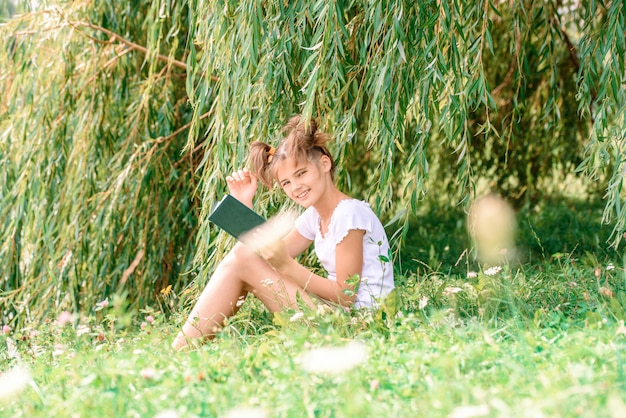 Little girl reading a book with her friend puppy dog in the outdoors.