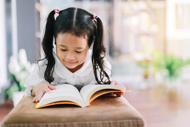 Little girl reads a book in her room. Education children concept.