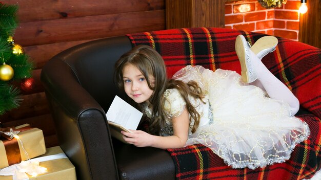 Little girl reads a book with interest.