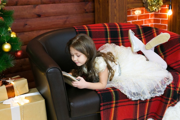 Little girl reads a book with interest.