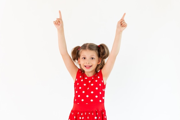 A little girl in a red dress points up at your ad on an isolated white background;