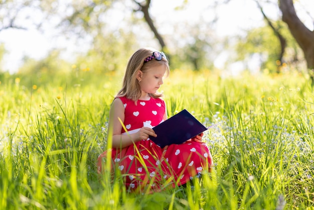 Little girl in a red dress reads a book