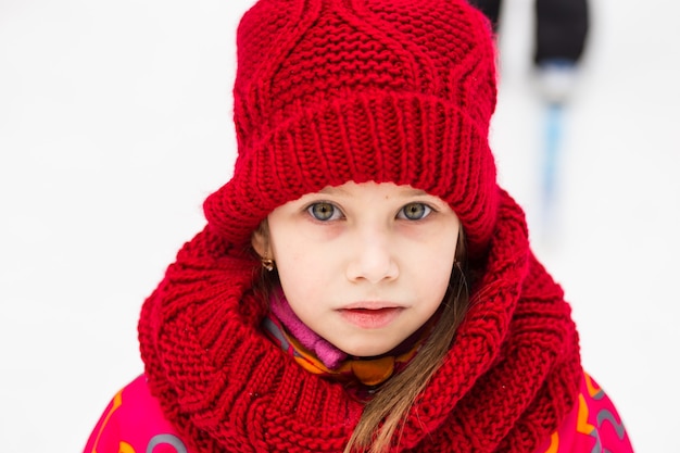 Little girl in a red wool hat in winter park