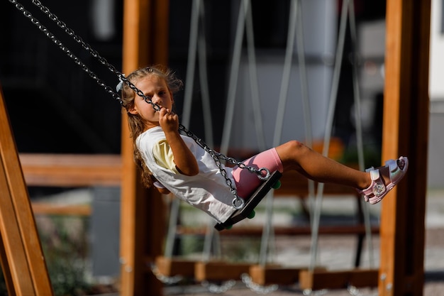 Little girl ride on a swing near the house