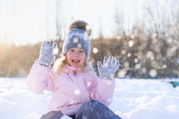 Little girl rides down the slide on the ice cheerful child emotions from winter fun