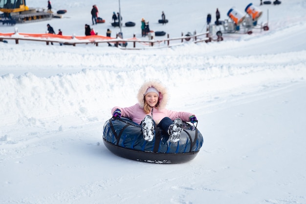 A little girl rides a tubing down a slide