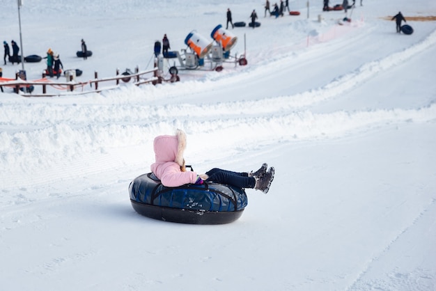 A little girl rides a tubing down a slide