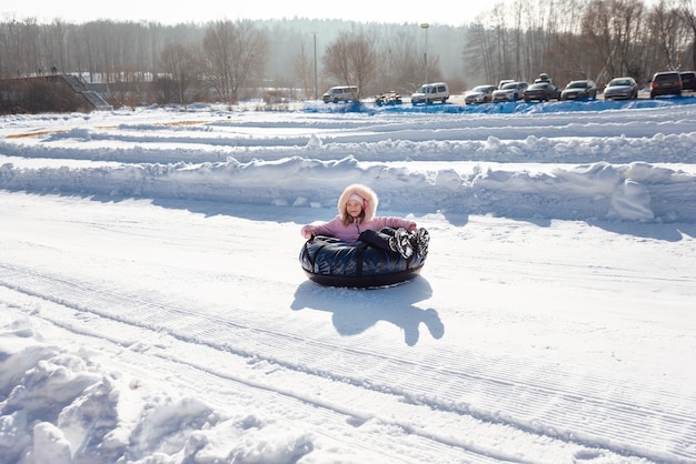 A little girl rides a tubing down a slide