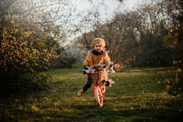 Little girl riding a red bike in the park in early spring