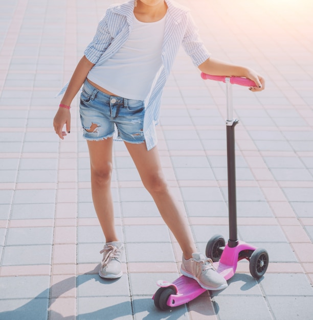 Little girl riding scooter outdoors. Street urban