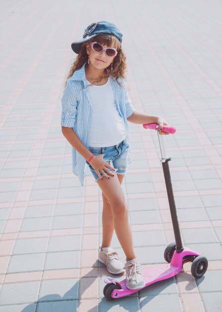 Little girl riding scooter outdoors.