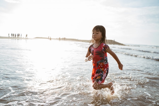 Little girl running on the beach while playing water