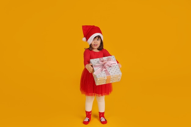 a little girl in a Santa Claus hat holding a gift box concept for the new year