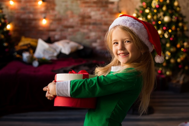 Little girl in Santa hat holding a gift box