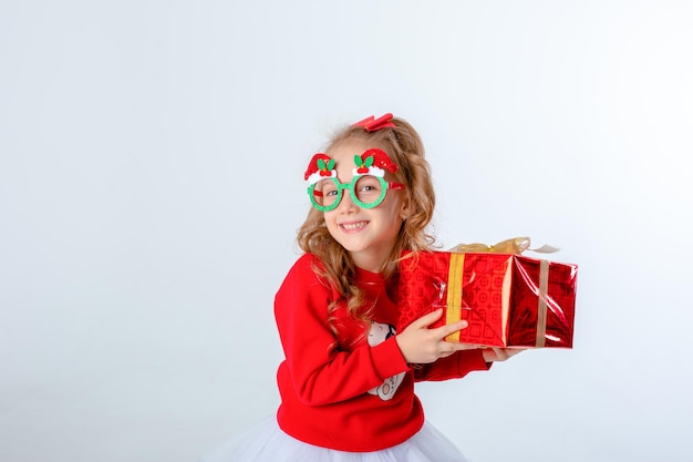 Little girl in santa hat holds a gift on white background Christmas concept text space