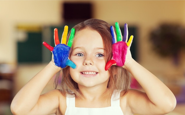 Little girl showing painted hands on blackboard background