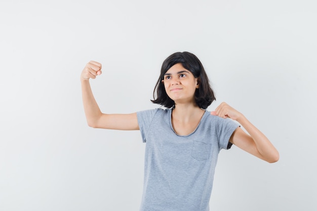 Little girl showing winner gesture in t-shirt and looking blissful , front view.