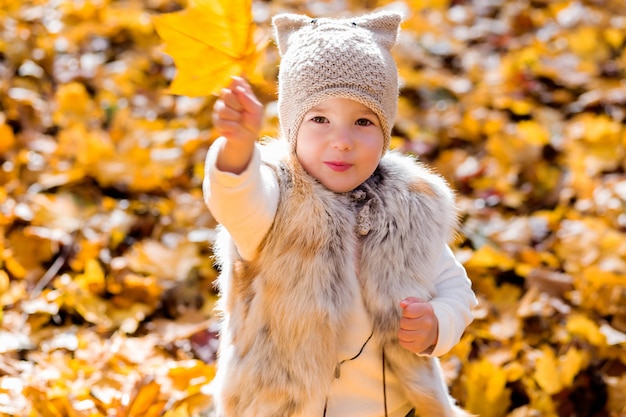 Little girl shows autumn leaf