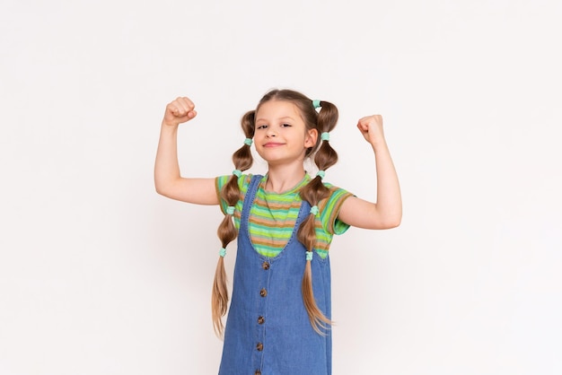 The little girl shows how strong she is The child shows his biceps on a white isolated background