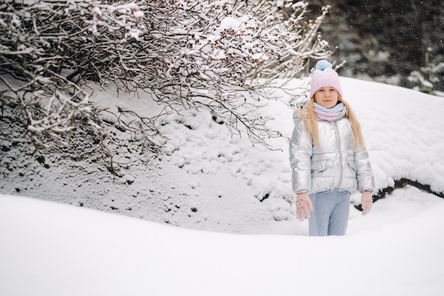 A little girl in a silver jacket in winter goes outside in winter