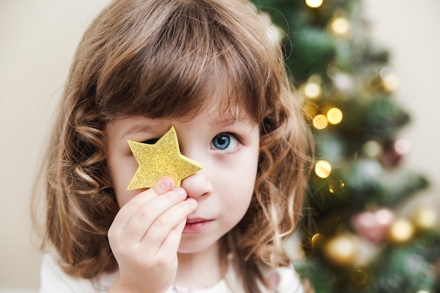 little girl sitting beside decorated Christmas tree