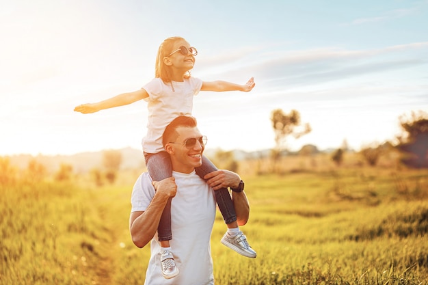 Little girl sitting on father's shoulders and laughing