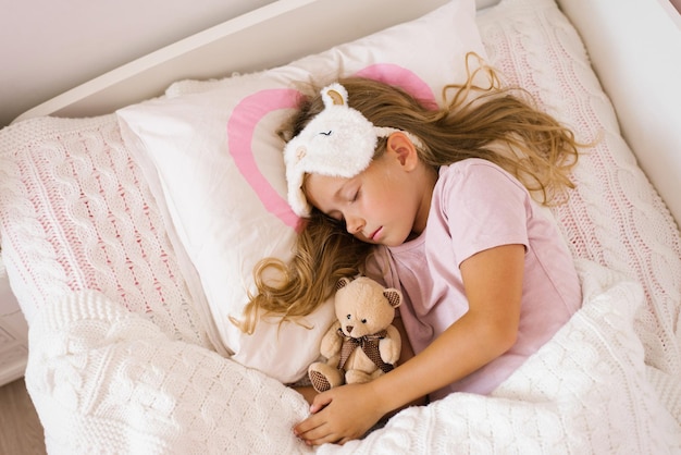 Little girl sleeping with a soft toy in her bed on a pillow is a sweet calm sleep of a child