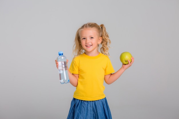 little girl smiling holding an Apple and a bottle of water