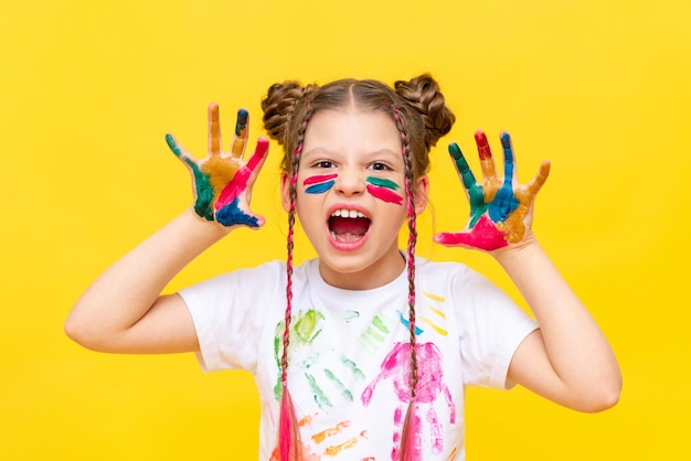 A little girl stained in multicolored paints portrays a growling beast The art of painting with paints for children School creative courses for teenagers