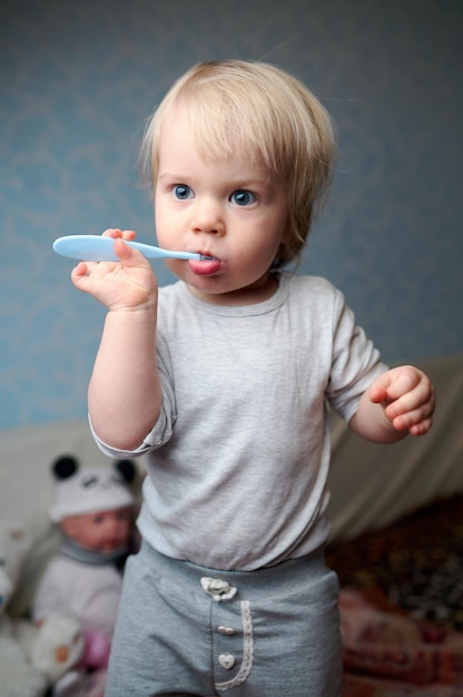 A little girl stands and brushes her teeth with a brush home atmosphere