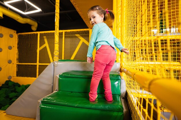 Little girl step up in stairs at yellow playground park Child in active entertaiments