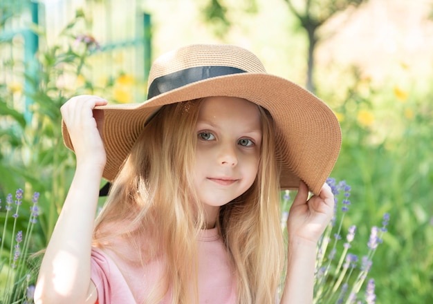 Little girl in a straw hat surrounded by lavender flowers