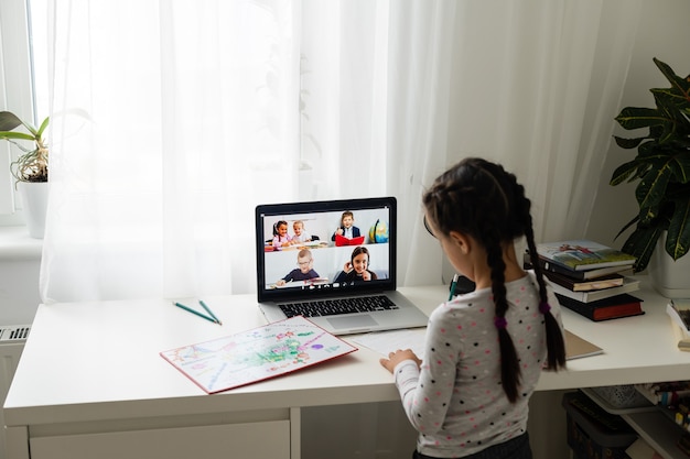 Little girl studying online using her laptop at home