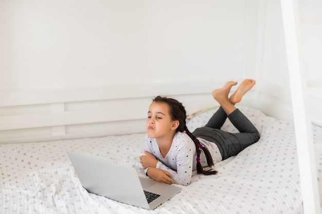 Little girl studying online using her laptop at home