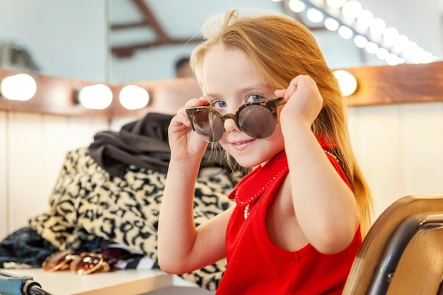 Little girl in sunglasses near mirror