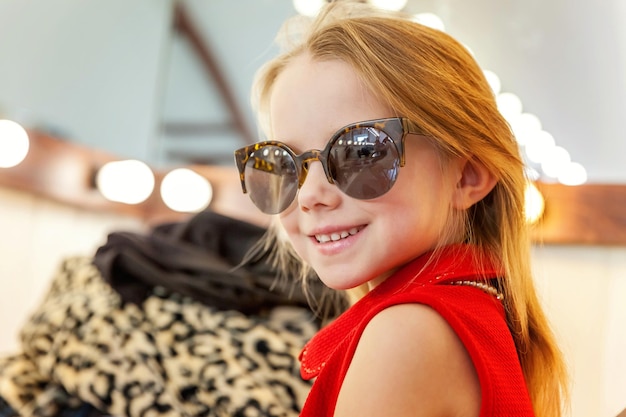 Little girl in sunglasses near mirror