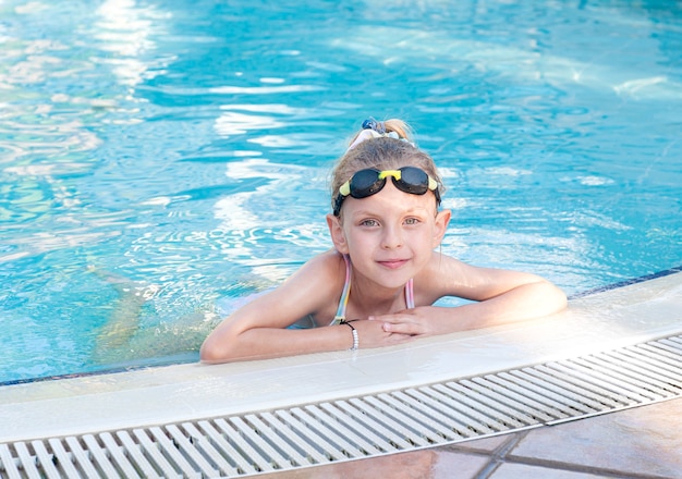 Little girl in swimming goggles swims in the pool