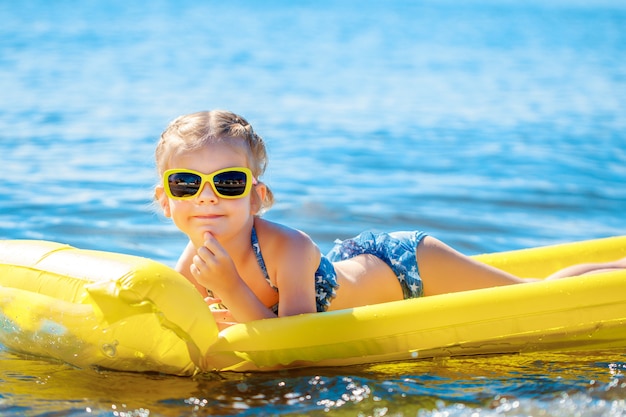 Little girl swimming on inflatable beach mattress.