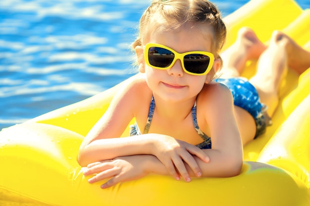 Little girl swimming on inflatable beach mattress.