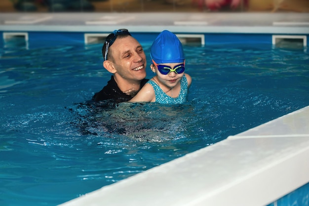 Photo little girl in swimming lessons in the pool with a coach